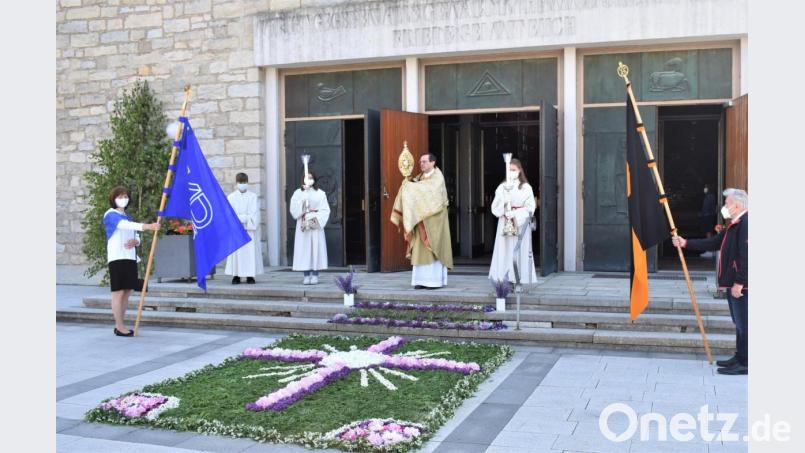 Mitglieder des Katholischen Frauenbundes legen am Fronleichnamstag einen Blumenteppich vor der Friedenskirche. Nach dem Festgottesdienst ohne Prozession erteilt Pfarrer Bernhard Müller vor dem Gotteshaus mit der Monstranz den Segen für die ganze Stadt. Bild: rgr