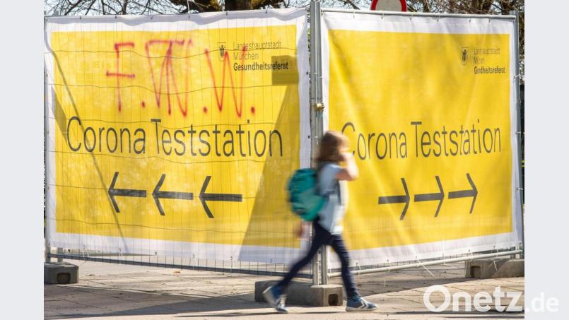 Große gelbe Banner mit der Aufschrift „Corona Teststation“ hängen an Absperrgittern an der Theresienwiese in München. Bild: Peter Kneffel/dpa