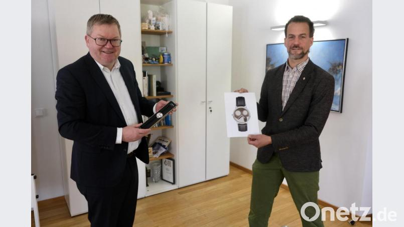Oberbürgermeister Michael Cerny (links) hält das Original der neuen Stadt-Uhr in seinen Händen, Goldschmied Sebastian von der Recke (rechts) eine fotografische Vergrößerung. Bild: usc