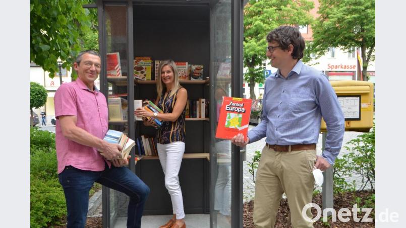 Bürgermeister Uli Münchmeier (rechts) hält einen alten Atlas in der Hand, der im begehbaren Bücherschrank nichts verloren hat. Büchereileiterin Tanja Ries (Mitte) bestückte den Schrank. Mit im Bild Amtsbote Alexander Kießling. Bild: dob