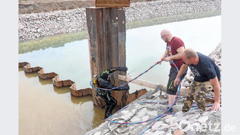 Gar nicht so einfach in voller Montur aus dem Wasser zu steigen. Taucher Rainer Dietl muss die Spundwände (links im Wasser zu sehen) der Düker-Baugrube abschneiden. Auch unter Wasser eine schweißtreibende Arbeit. Bild: Gabi Schönberger