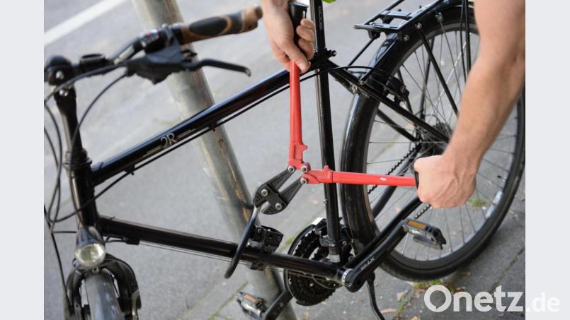 Ein Mann versucht mit einem Bolzenschneider ein Fahrradschloss aufzubrechen. Symbolbild: Andreas Gebert/dpa