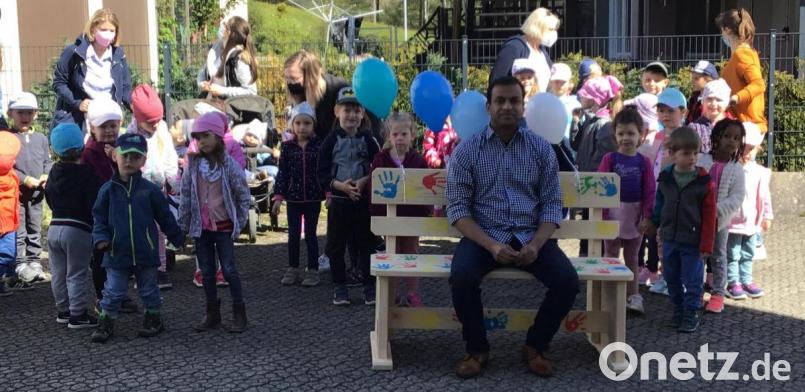 Pfarrer Anish George auf seiner neuen Ruhebank, die er von den Kindern des Kinderhauses erhalten hat Bild: soj
