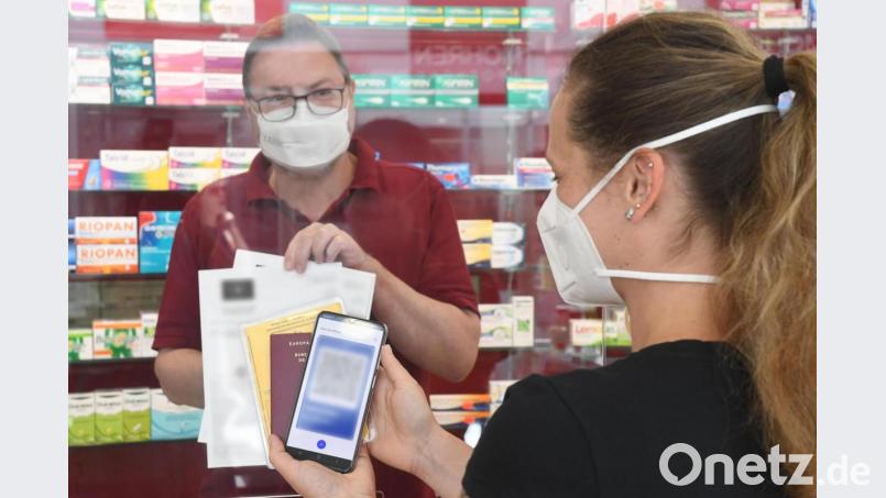 Nadine Paulus lässt sich in der Mohren-Apotheke in Weiden von Apotheker Andreas Biebl den QR-Code für den digitalen Impfnachweis ausstellen. Bild: Gabi Schönberger