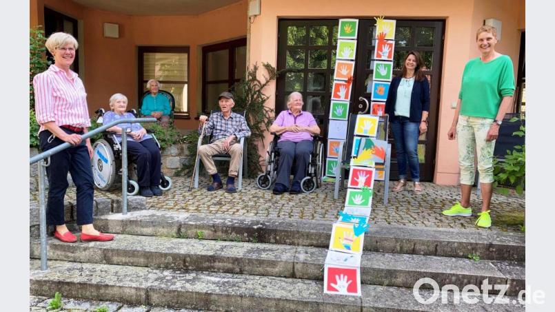Am Tag der Nachbarschaft eine Strickleiter aus gebastelten Händen übergeben: Barbara Hernes (links) vom Sozialmosaik Naturpark Hirschwald, Schulleiterin Ulrike Hampel-Sperlich (Mitte) und Heimleiterin Monika Breunig (rechts) mit einigen Senioren. Bild: jp