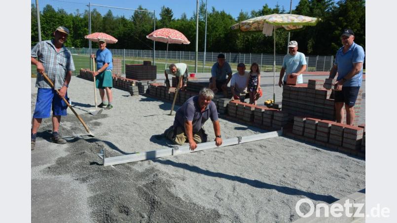 Kräftig mit angepackt haben Mitglieder der Sparte Eisstock des SV Steinmühle, um zusammen mit dem erfahrenen Stockbahnbauer Georg Birgmeir aus Oberbayern (kniend) eine neue Anlage auf dem Sportgelände zu errichten. 12 325 Pflastersteine galt es in mehreren Tagen zu verlegen. Bild: jr