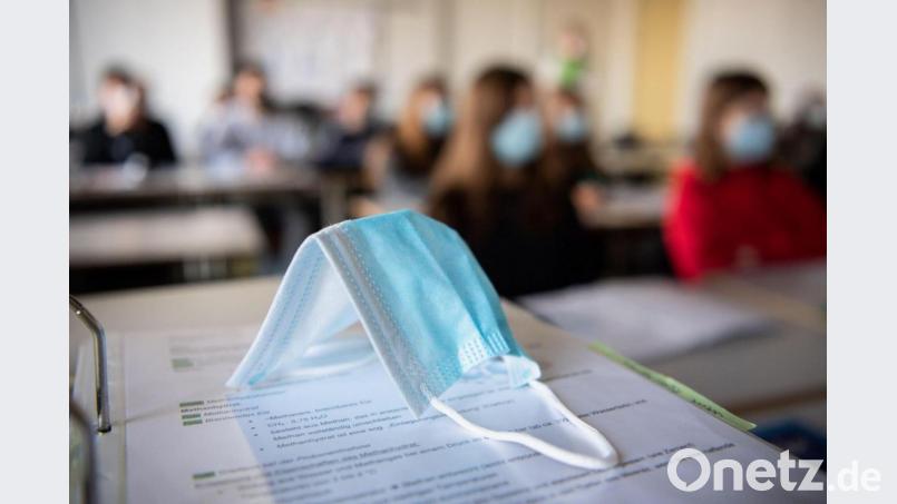 Eine Maske liegt im Unterricht an einem Gymnasium in München auf Schulunterlagen. Bild: Matthias Balk/dpa