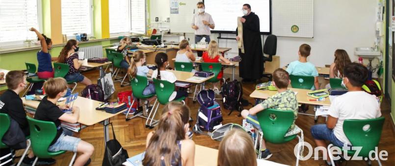 Pater Michael (stehend, rechts) stellte sich den Fragen der Schüler. Mit auf dem Bild Pfarrer Martin Besold (stehend, links). Bild: njn