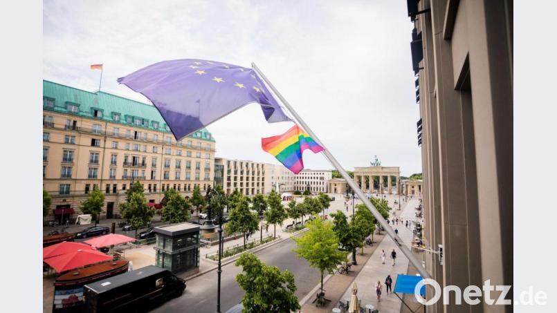 Eine Regenbogenfahne weht am Mittwoch neben der EU-Flagge an der Vertretung der Europäischen Kommission in Berlin. Die EU-Kommission geht gegen Ungarns Gesetz zu Sexualität vor. Bild: Christoph Soeder/dpa