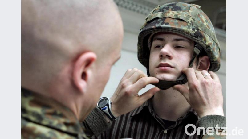 Ein Bundeswehrsoldat hilft im April 2005 einem gerade eingezogenen Kameraden den Helm aufzusetzen. Archivbild: Frank May