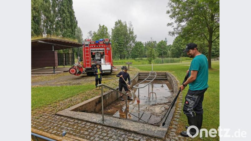 Die Feuerwehrleute Jürgen Bösl und Maximilian Hochwart unterstützen den Bauhof bei der Säuberungsaktion am Kneippbecken. Alles genau im Blick hatte der siebenjährige Florian Bösl, der wie sein Papa ebenfalls Feuerwehrmann werden möchte. Bild: gz