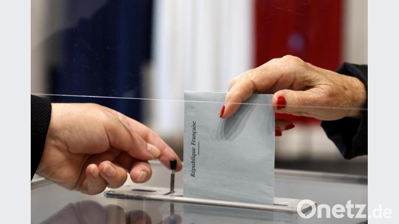 Eine Person wirft bei den Regionalwahlen in Frankreich ihren Stimmzettel in eine Wahlurne. Bei der entscheidenden Runde der Abstimmung am Sonntag lag die Beteiligung auch in Libourne und Castillon-la-Bataille bei nur etwa einem Drittel. Bild: Ludovic Marin/dpa