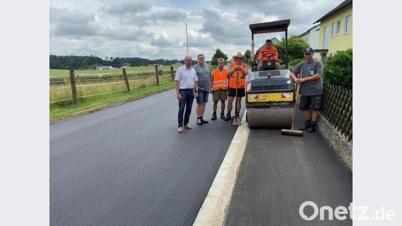 Ein Bild von der sanierten Siedlerstraße machen sich vor Ort Bürgermeister Roland Strehl, der gemeindliche Bautechniker Michael Pollok (von links) und Mitarbeiter der ausführenden Firma Englhard. Bild:  Hans Oberndorfer/exb