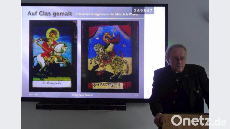 Dr. Reiner Reisinger referiert über die Winklarner Hinterglaskunst. Während des Vortrags sind hinter ihm zwei Darstellungen des heiligen Georg in zwei verschiedenen Malweisen zu sehen: links ein Bild der Winklarner Schule, rechts die Schönsteiner Malweise. Bild: amö
