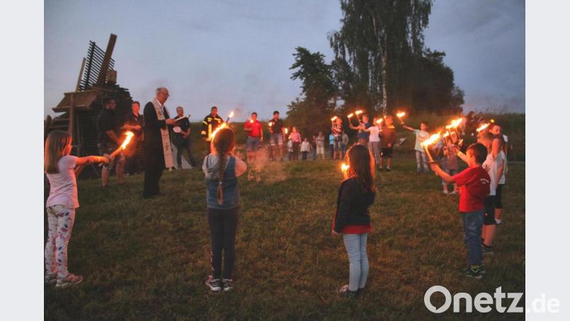 Mit den Kindern und Jugendlichen segnete Pfarrer Herbert Rösl das Feuer. Mit den Fackeln wurde das Feuer dann entzündet. Bild: tkr