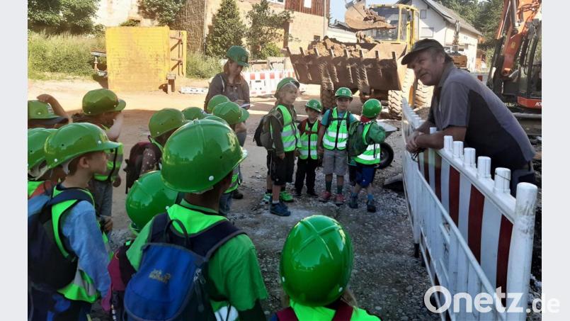 Polier Thomas Kirchner von der Firma Mickan (rechts) beantwortet die Fragen der Räuberwaldkinder, die mit Erzieherin Lisa Dilling (Mitte) die Baustelle besuchen. Bild: Sabine Lindner/exb