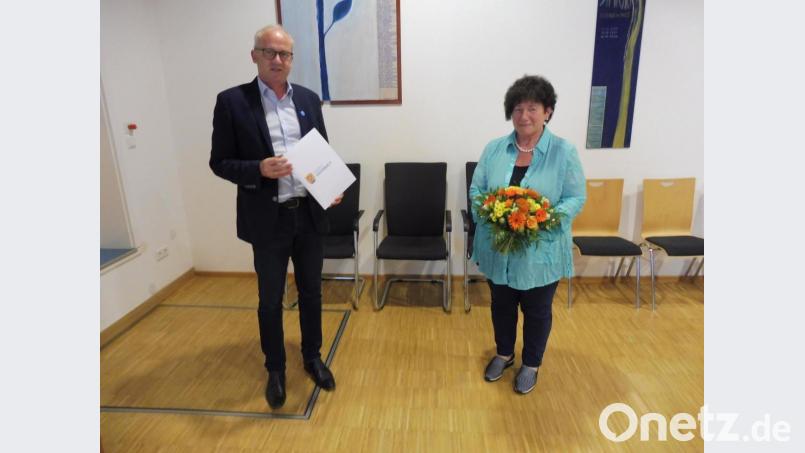 Für 25 Jahre im Marktgemeinderat dankte Bürgermeister Bernhard Lindner (links) Brigitte Trummer mit einer Urkunde und einem Blumenstrauß. Bild: ibj