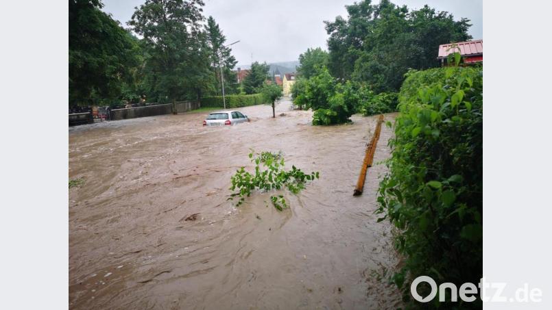 Ein Fahrzeug ist auf einer überfluteten Straße von Hochwasser umgeben. In Wilhermsdorf waren Menschen teilweise bis Samstagmittag ohne Strom. Bild: Vifogra/dpa