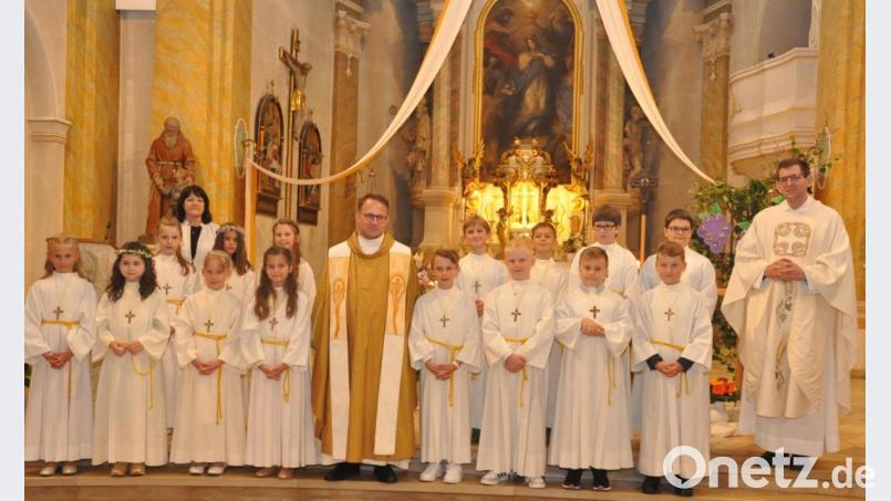 Dekan Alexander Hösl (Mitte) und Kaplan Alexander Ertl (rechts) feierten zusammen mit den Kindern Erstkommunion. Grundschullehrerin Birgit Pruy (hinten, links) begleitete die Kinder zu diesem großen Erlebnis. Bild: dob
