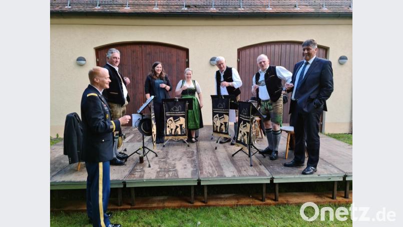 Colonel Christopher Danbeck (links) darf mit Bürgermeister Edgar Knobloch (rechts) und der &quot;Hammerschloss-Musi&quot; ein weinig &quot;schnapseln&quot;. Bild: sne