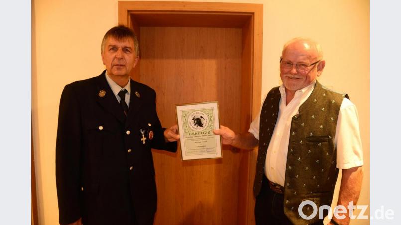 Vorsitzender Johann Kellner überreicht Josef Schärtl die Ernennungsurkunde zum Ehrenmitglied der Feuerwehr Döllnitz, Markt Leuchtenberg. Bild: bey