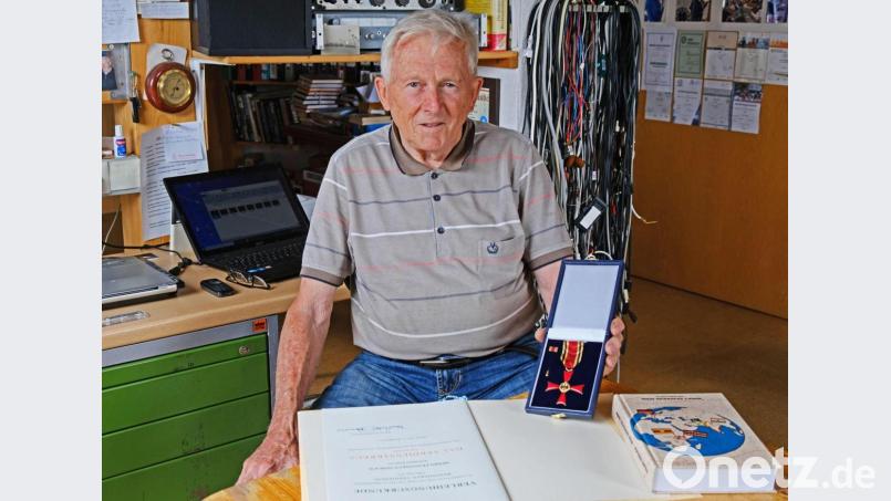 Franz Neblich präsentiert sein Verdienstkreuz am Bande mit Urkunde, daneben sein Buch &quot;Mein bewegtes Leben&quot; in seinem elektrotechnischen Studio, das mit zahlreichen Geräten ausgestattet ist. Bild: twi