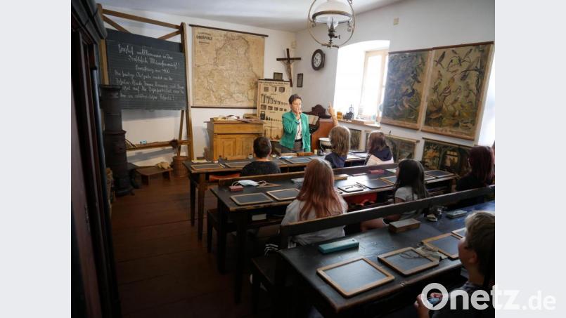 Gabriele Achmann mit einer Gruppe im Klassenzimmer der alten Dorfschule von Münchenreuth, das im Stiftlandmuseum wieder nahezu originalgetreu aufgebaut ist. Bild: hmr