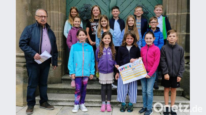 Katharina, Julia, Marie, Elisa, Fanny, Anne, Mila, Sophie, Celina, Paul, Hannes, Jonas, Max, Simon, Stefan und Anton: Gemeinsam überreichen die Erstkommunikanten nach dem Dankgottesdienst mit Pfarrer Adrian im Klosterhof an Andreas Steinl den symbolischen Spendenscheck für die Kinderkrebshilfe. Bild: do