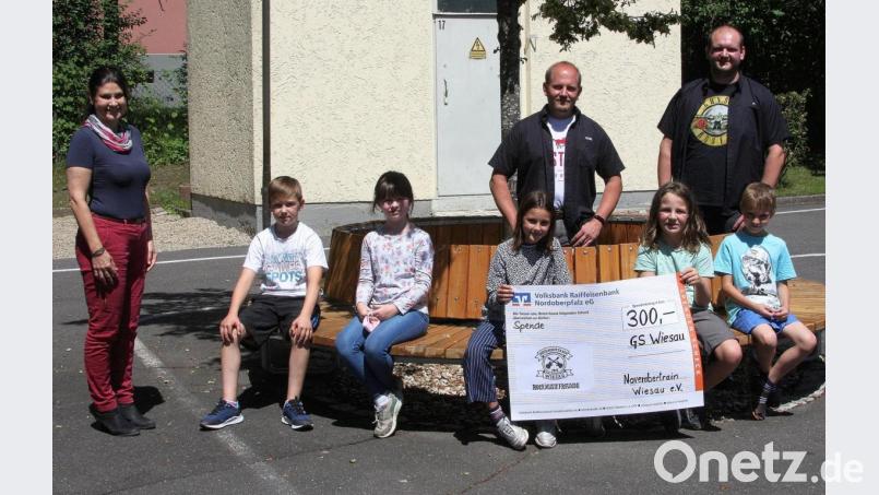 Rektorin Inge Dick (links) und Kinder aus den drei Grundschulen übernahmen vom Vorsitzenden des Vereins &quot;November (T)rain&quot;, Benjamin Meyer, und Schriftführer Florian Greil (hinten von links) eine Spende in Höhe von 300 Euro. Die Spendenübergabe fand im Pausenhof der Grundschule Wiesau statt. Bild: wro