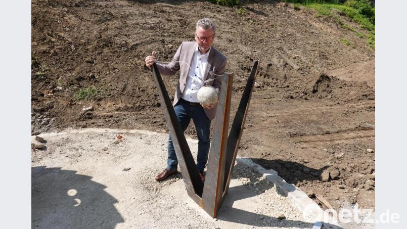 Bürgermeister Michael Göth testet das Gewicht der Original-Kanonenkugel aus dem Landshuter Erbfolgekrieg, die bei einem Drachensegment aufgehängt ist. Bild: gac