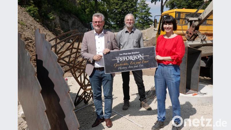 Bürgermeister Michael Göth, Planer uind Bauleiter Josef Starkl und Architektin Christine Schaller-Kokesch (von links) enthüllen auf der Baustelle den Namen des Geschichtsdrachens. Bild: gac