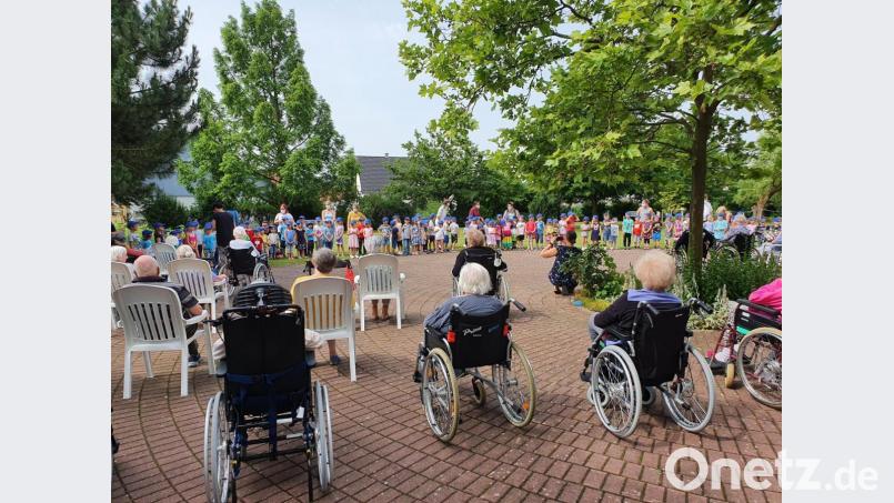 Im Garten des AWO-Heimes unterhalten die Mädchen und Buben der Kindertagesstätte Arche Noah die Senioren mit Liedern. Bild: e