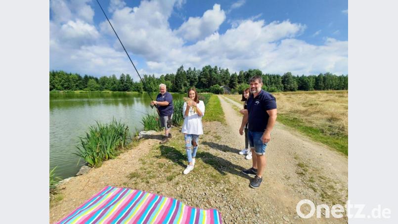 Mit dem Anglergruß gratulierten Martin Forster und Thomas Höreth (re) der Schülerin Christina zu ihrem gefangenen Karpfen. Bild: gz