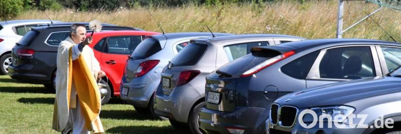 Pfarrer Eduard Kroher nutzt die Gelegenheit, nach dem Freigottesdienst bei der Donatuskapelle. die auf dem Bolzplatz abgestellten Fahrzeuge zu segnen und sie unter den Schutz des heiligen Christoph zu stellen. Bild: sche