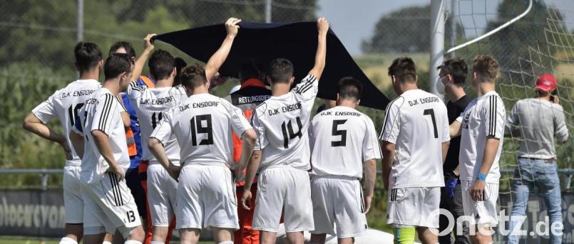 Die Spieler der DJK Ensdorf halten eine Plane über ihren verletzten Torhüter Maximilian Hauer, als dieser von den Rettungskräften versorgt wird. Bild: Hubert Ziegler