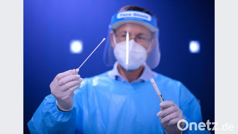 Ein Arzt hält in einer Corona-Teststation für Urlaubsrückkehrer einen Coronavirus-Test in den Händen. Symbolbild: picture alliance/Robert Michael/dpa-Zentralbild/dpa