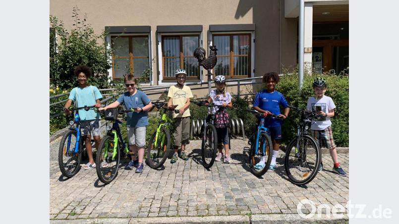 Fahrrad und Handy parat: Die Actionbound-Tester starten das Hahnbacher Abenteuer bei der Jubiläumsfahne vor dem Rathaus. Bild: Katja Stiegler/exb