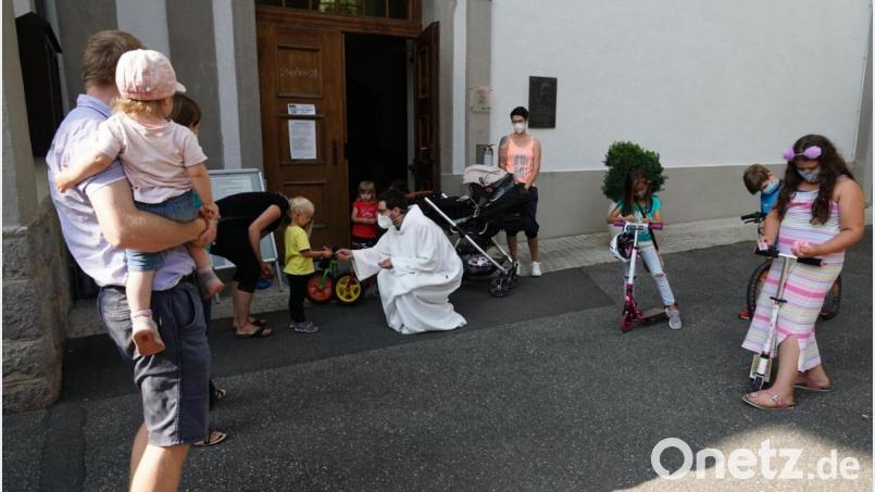 Pastoralreferent Andreas Hornauer klebt kleine Christophorus-Plaketten auf die Kinderfahrzeuge. Bild: ads