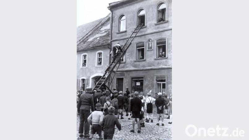 Zu den Vorführungen der Feuerwehr gehörte auch das Retten aus dem 2. Stock des Anwesens Bauer am Marktplatz. Feuerwehrmann Heuberger hat den jungen Albert Zach (später Bäckermeister) auf dem Rücken. Bild: u