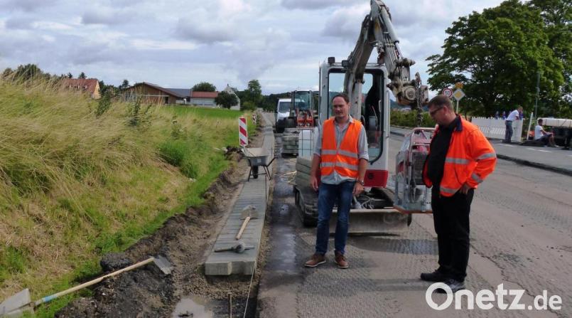 Technischer Amtsrat Stefan Weiß (links) und Baudirektor Stefan Noll begutachten die Verlegung der massiven, überfahrbaren Bordsteine, die nur mit dem Klein-Bagger verlegt werden können, da ein Stein 150 Kilo wiegt. Bild: jp