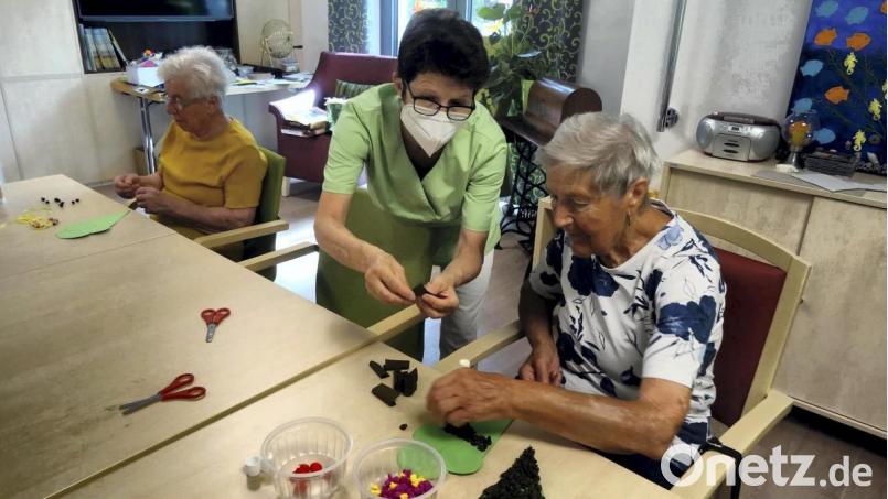 Die Aufgabe in der Tagespflege der Ökumenischen Sozialstation lautet: eine Eistüte basteln. Schwester Elisabeth hilft den Seniorinnen dabei. Bild: hka
