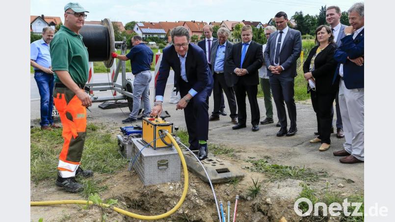 Bundesverkehrsminister Andreas Scheuer (Zweiter von links) lässt vor den Augen von MdL Joachim Hanisch, Bürgermeister Benjamin Boml, MdB Marianne Schieder, Landrat Thomas Ebeling und Bürgermeister Thomas Gesche (von rechts) eine Maschine Glasfaserleitungen in Leerrohre schieben. Franz Kerscher (links, Firma rke) passt auf, das alles klappt. Bild: Hösamer