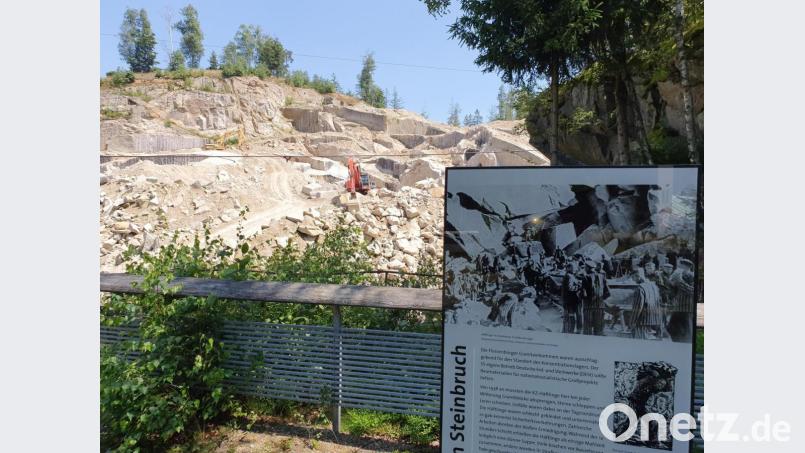 Auf der Aussichtsplattform erklären Schautafeln, dass hier im Steinbruch Wurmstein schlimme Dinge passiert sind. Im Hintergrund die Maschinen, die noch immer Granit im ehemaligen KZ-Steinbruch abbauen. Bild: Würth, Wolfgang