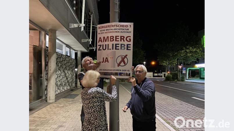 Der Laternenpfahl vor dem Café Kult in der Marienstraße ist für die Plakatierer der IG Menschengerechten Stadt mit Achim Hüttner (links) und Norbert Scharf (rechts) der ideale Ort. Bild: Andreas Ascherl