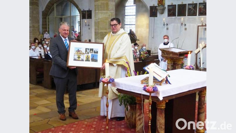 Während der Festmesse zum Patrozinium St. Mariä Himmelfahrt überreicht Pfarrgemeinderatsvorsitzender Richard Reisinger eine Fotocollage an Pfarrer Walter Hellauer. Bild: müb