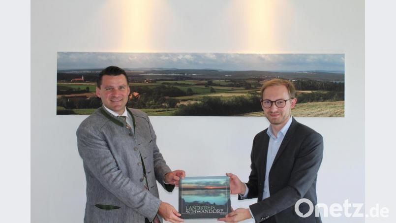 Landrat Thomas Ebeling (links) schenkte Manuel Köppl (rechts) ein Buch aus dem Landkreis Schwandorf. Bild: Manuel Lischka/exb