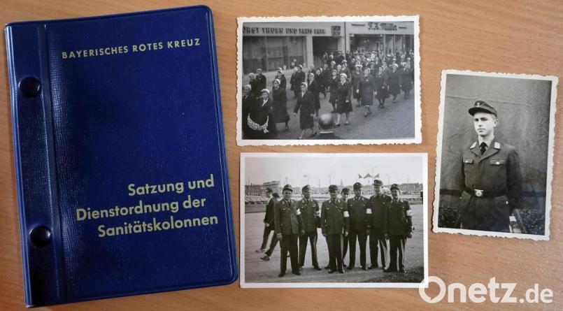 Relikte aus Erhard Hirmers Anfangszeit beim Roten Kreuz in Amberg: Neben dem Büchlein mit der Dienstordnung der Sanitätskolonnen liegen alte Fotos. Sie zeigen eine Abordnung der Sanitätskolonne Amberg beim eucharistischen Weltkongress 1960 in München, Rotkreuz-Helferinnen bei einem Festzug in Amberg und Hirmer selbst in Rot-Kreuz-Uniform. Bild: Wolfgang Steinbacher