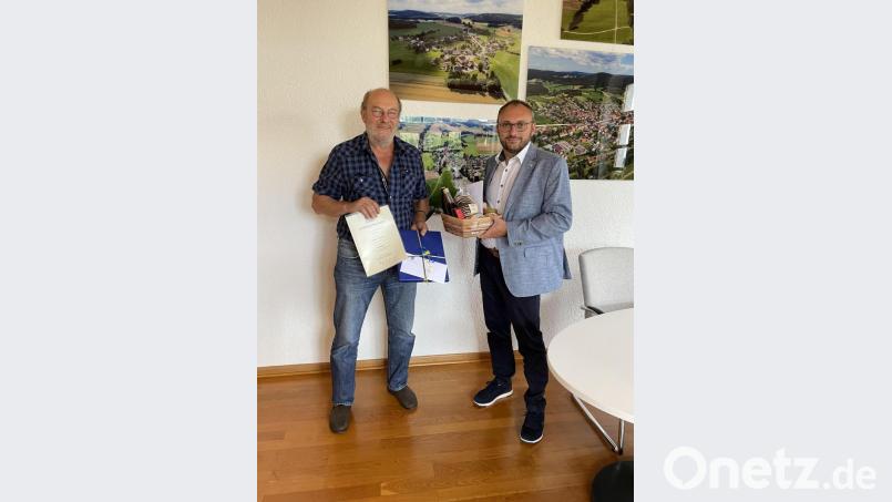 Vor den neuen Luftaufnahmen im Bürgermeisterzimmer des Rathauses überreicht Markus Bauriedl an Hermann Schmidt (links) sinngebend die Auszeichnung des bayerischen Finanz- und Heimatministeriums. Bild: fjo