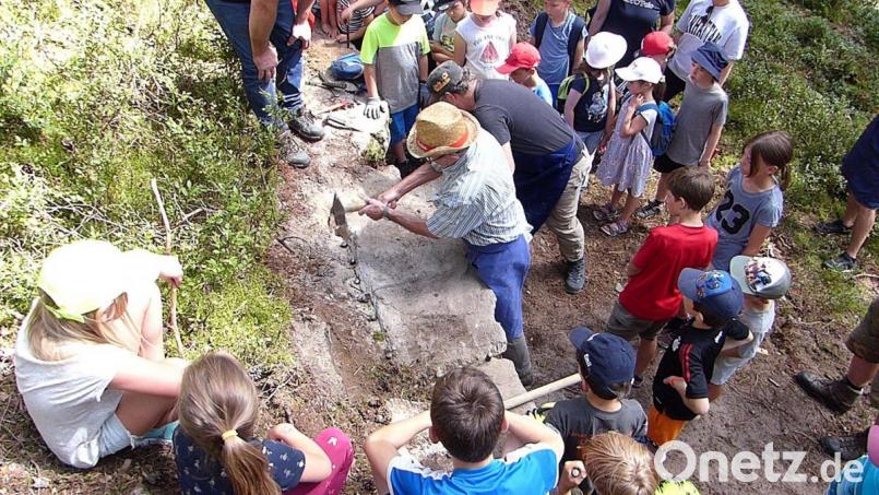 Steinbrechen wie in alten Zeiten: Per Muskelkraft wird ein etwa 300 Kilogramm schwerer Sandstein aus dem alten Steinbruch gelöst. Die Kinder beobachten begeistert das Spektakel. Bild: lgc