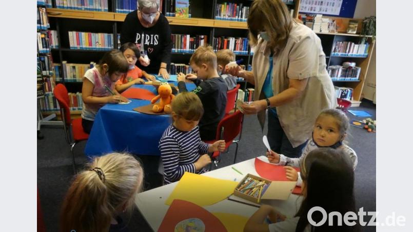 Der kleine Drache Kokosnuss schaut zu, als die künftigen Erstklässler in der Stadtbibliothek mit Unterstützung von Karin Reul und Renate Schneider-Kaus (von rechts) Kleine-Drache-Kokosnuss-Schultüten basteln. Bild: rn